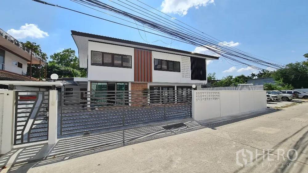 บ้านเดี่ยว for rent in Lat Phrao, Bangkok - ด้านหน้าบ้านพร้อมประตูรั้วเหล็กสไลด์และลานจอดรถคอนกรีต