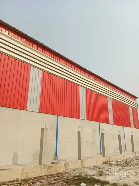 货栈 出租在Pathum Thani - 仓库外立面为红灰金属板并配混凝土基墙，位于Pathum Thani的Khlong Luang。