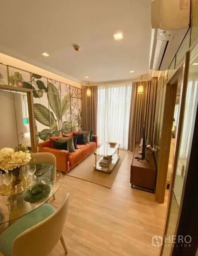 คอนโด ให้เช่าในWatthana, Bangkok - พื้นที่นั่งเล่นสว่าง โซฟาสีส้ม ชั้นวางทีวี และผ้าม่านโปร่งต่อเนื่องสู่ระเบียง