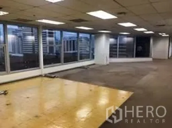 Office Space for rent in Bang Rak, Bangkok - Open-plan office floor with large windows, city skyline views, and suspended ceiling lights.