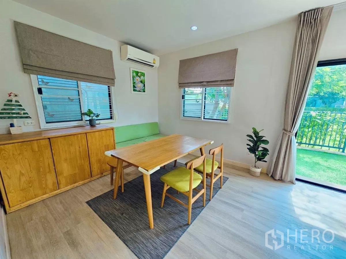Detached House for rent or sale in Don Mueang, Bangkok - Dining room with wooden table, green bench seating, and large windows.