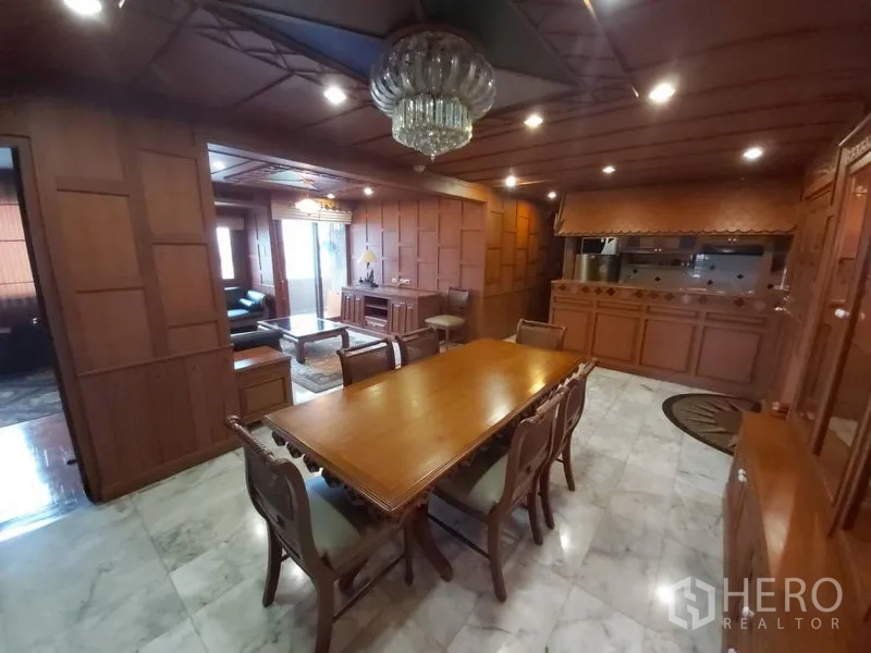 Condominium for rent in Samphanthawong, Bangkok - Open dining space with crystal light, wood walls and ceiling, marble floor, and view to living room and kitchen bar.