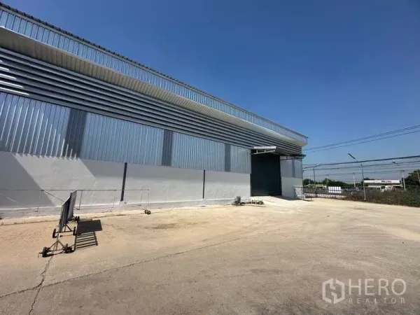 Warehouse for rent in Bang Bua Thong, Nonthaburi - Side elevation of the warehouse showing an expansive truck yard and perimeter fencing.