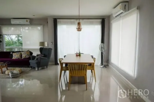 Detached House for rent or sale in Khlong Sam Wa, Bangkok - Dining space with wooden table, yellow chairs, floor-to-ceiling windows and air conditioning.