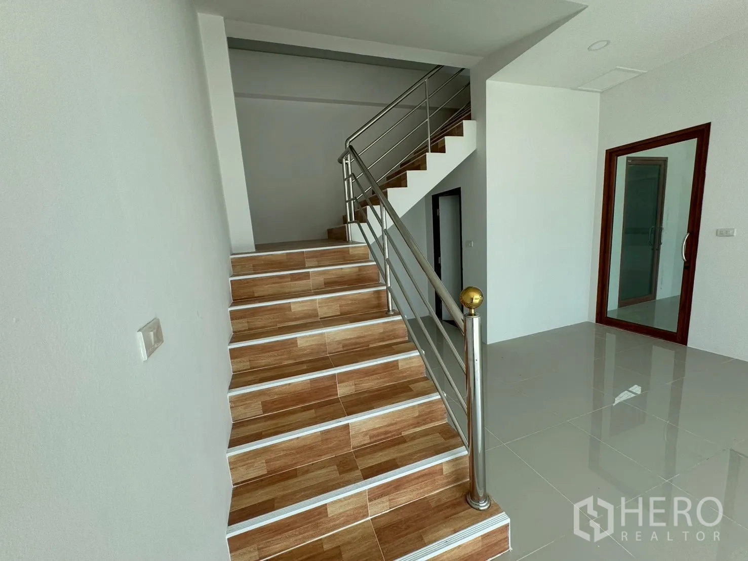 工厂 for sale in Mueang Samut Sakhon, Samut Sakhon - 一层大堂铺亮面瓷砖，配不锈钢扶手楼梯。