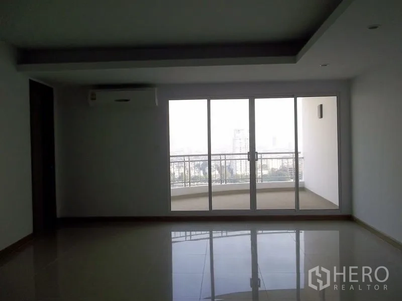 คอนโด ให้เช่าในBangkok - ห้องนั่งเล่นสว่างพื้นกระเบื้องเงาพร้อมประตูกระจกบานเลื่อนออกสู่ระเบียงกว้างวิวแม่น้ำในคอนโดสูง