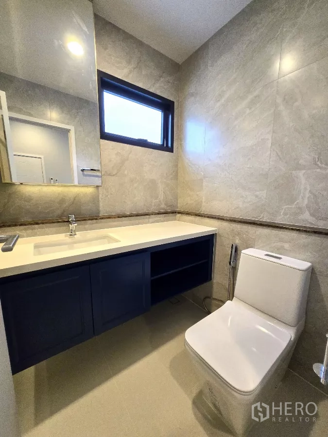 Detached House for rent in Bang Phli, Samut Prakan - Guest bathroom with stone-look tiles, wide vanity and toilet.