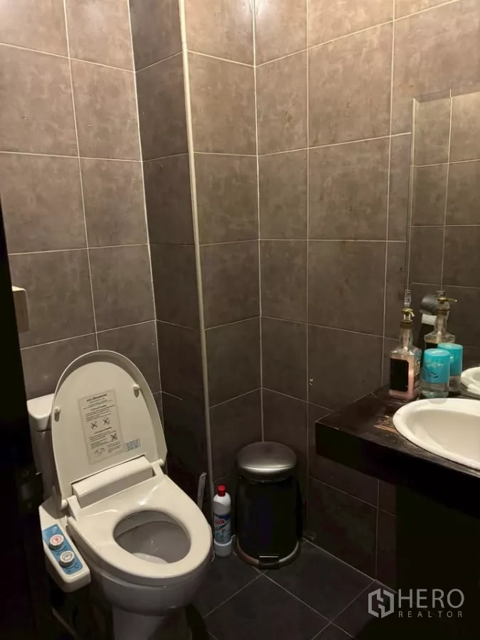 店屋 出租在Watthana, Bangkok - 深色瓷砖卫生间，马桶、洗手盆与镜子。
