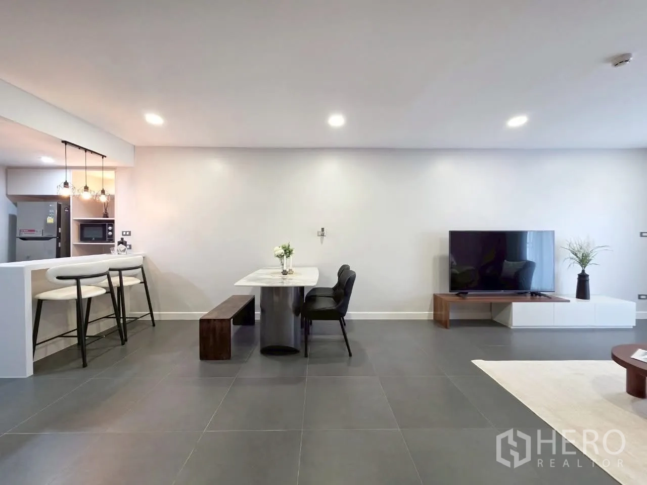 Condominium for rent in Sathon, Bangkok - Wide living-dining space with TV wall and bar seating.