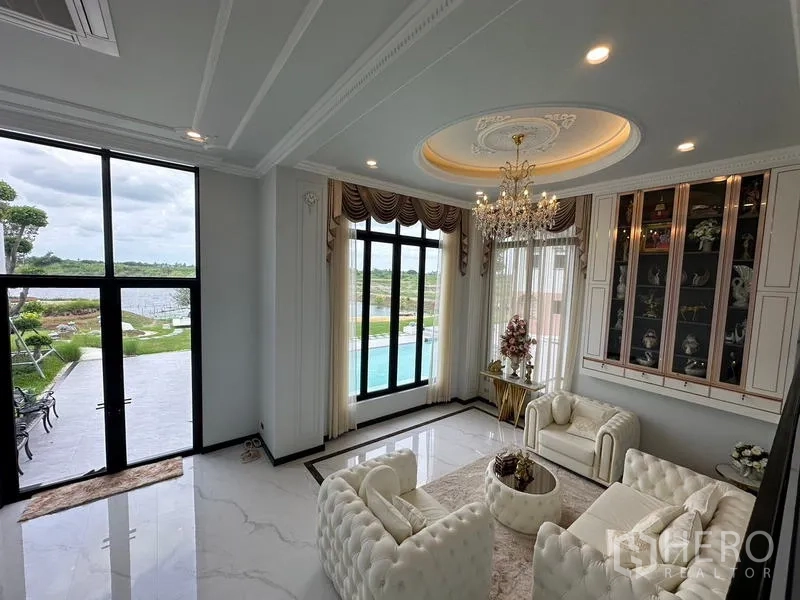 Detached House for sale in Sai Noi, Nonthaburi - Double-height living room with chandelier and pool view through tall windows.