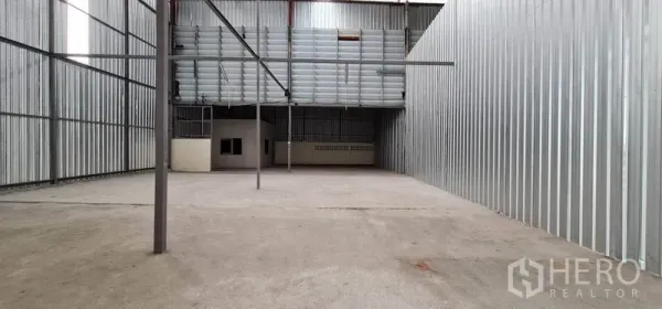 Warehouse for rent in Pak Kret, Nonthaburi - Empty warehouse bay with steel columns, translucent roof panels, and ample loading space.