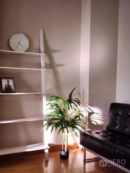 Condominium for rent in Khlong Toei, Bangkok - Cozy corner with ladder shelf, potted plant and black leather chair.