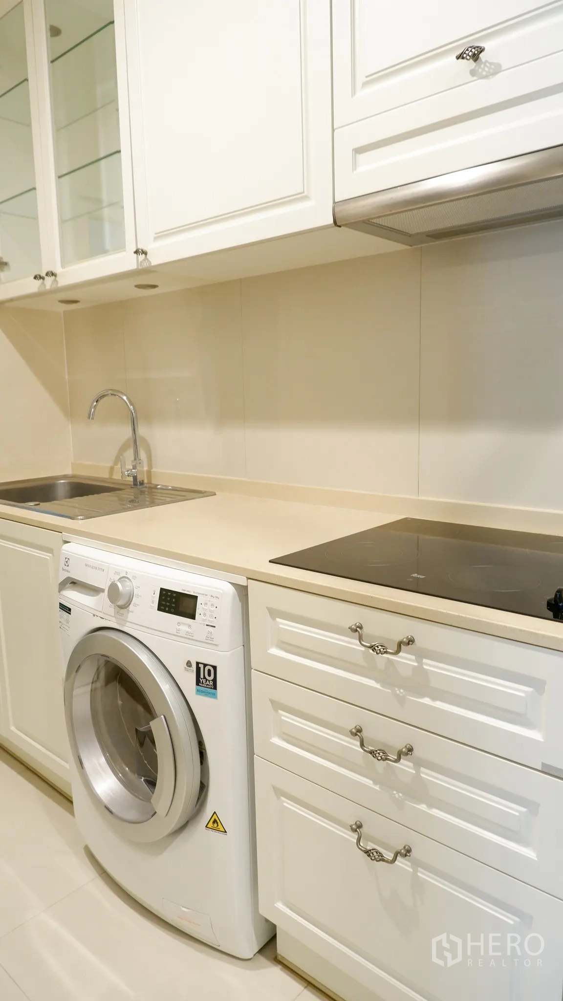 Condominium for rent in Watthana, Bangkok - Kitchen countertop with sink, induction hob and hood, plus front-load washer.