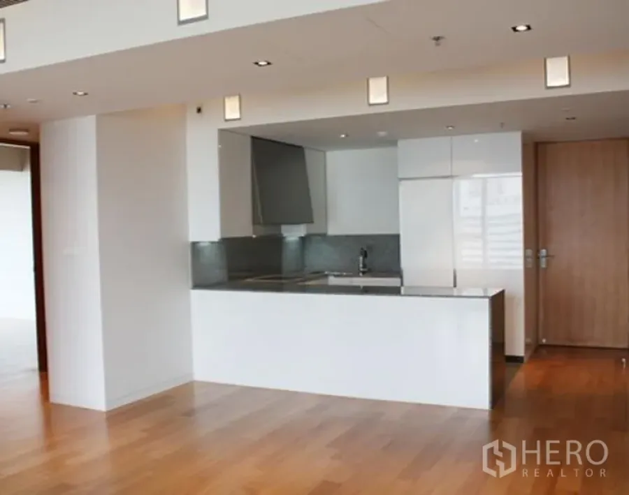 Condominium for sale in Sathon, Bangkok - Spacious open-plan room with white peninsula kitchen and wood floors, Sathon Bangkok.