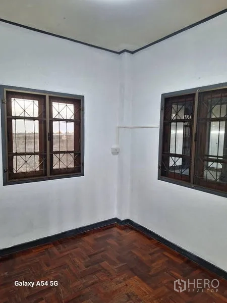 独立式住宅 出租在Bang Na, Bangkok - 明亮卧室转角，双窗与人字拼木地板。