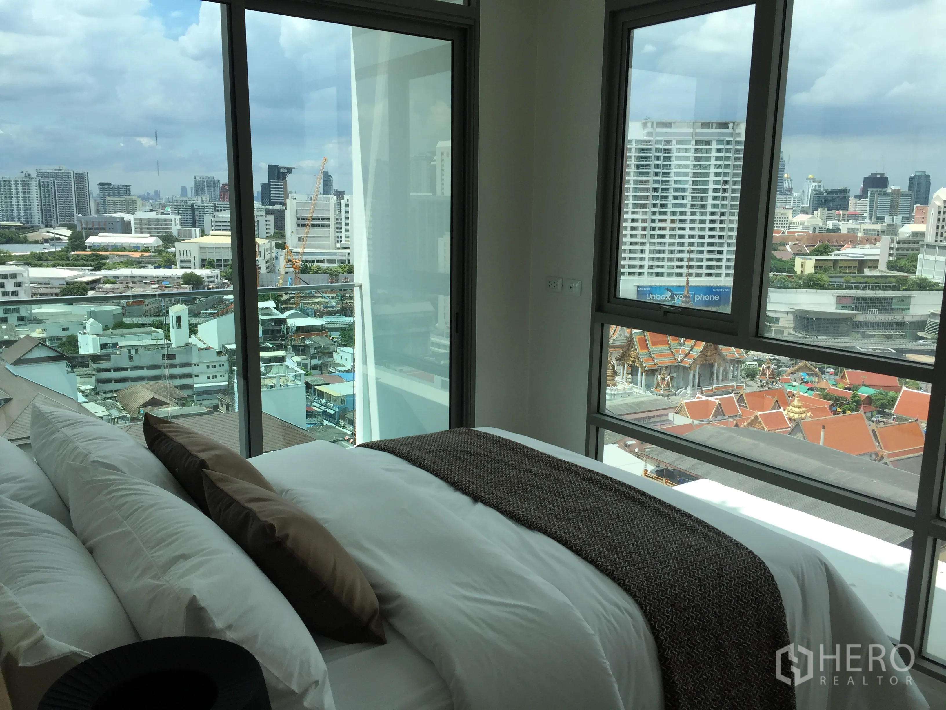 公寓 出售在Bang Rak, Bangkok - 转角卧室落地窗，俯瞰曼谷天际线与寺庙屋顶景观。