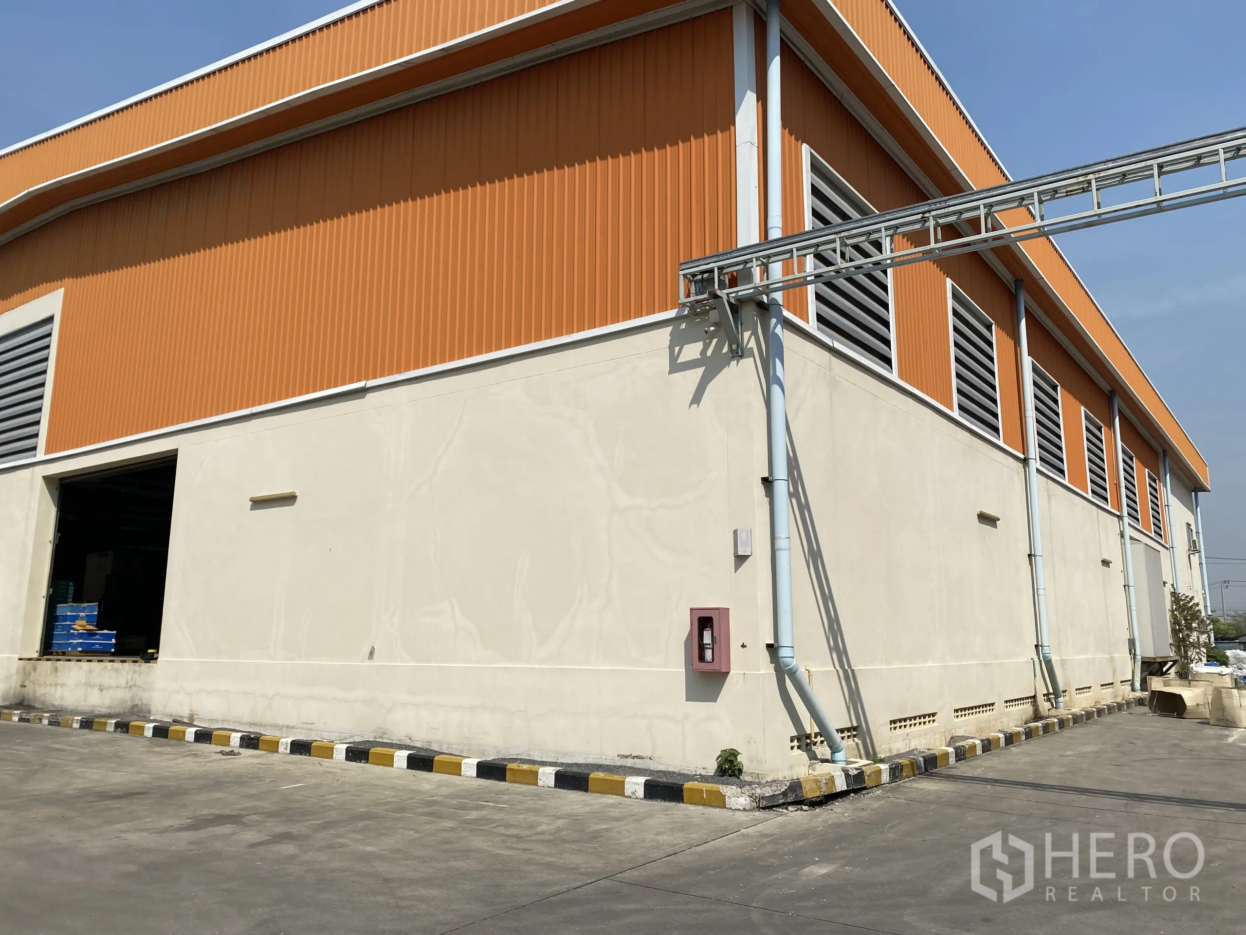 คลังสินค้า ให้เช่า - ผนังภายนอกโทนส้ม มีบานเกล็ดระบายอากาศ รางและท่อระบายน้ำ