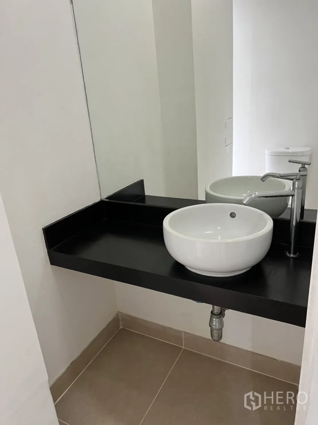 Shophouse for rent in Watthana, Bangkok - Modern bathroom vanity with round basin sink on a black countertop and mirror.