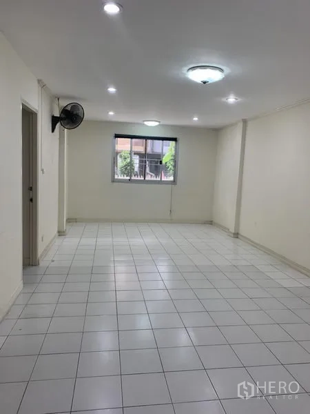Townhouse for rent in Wang Thonglang, Bangkok - Long living space with white floor tiles, window, ceiling lights and wall fan.