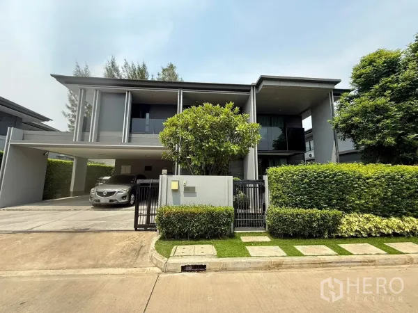 Detached House for rent in Bang Kapi, Bangkok - Modern two-storey detached house facade with gated entrance, hedge and covered three-car carport.