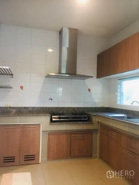 Detached House for rent in Bang Kapi, Bangkok - Separate U-shaped kitchen with granite countertops, stove, range hood and tiled walls.