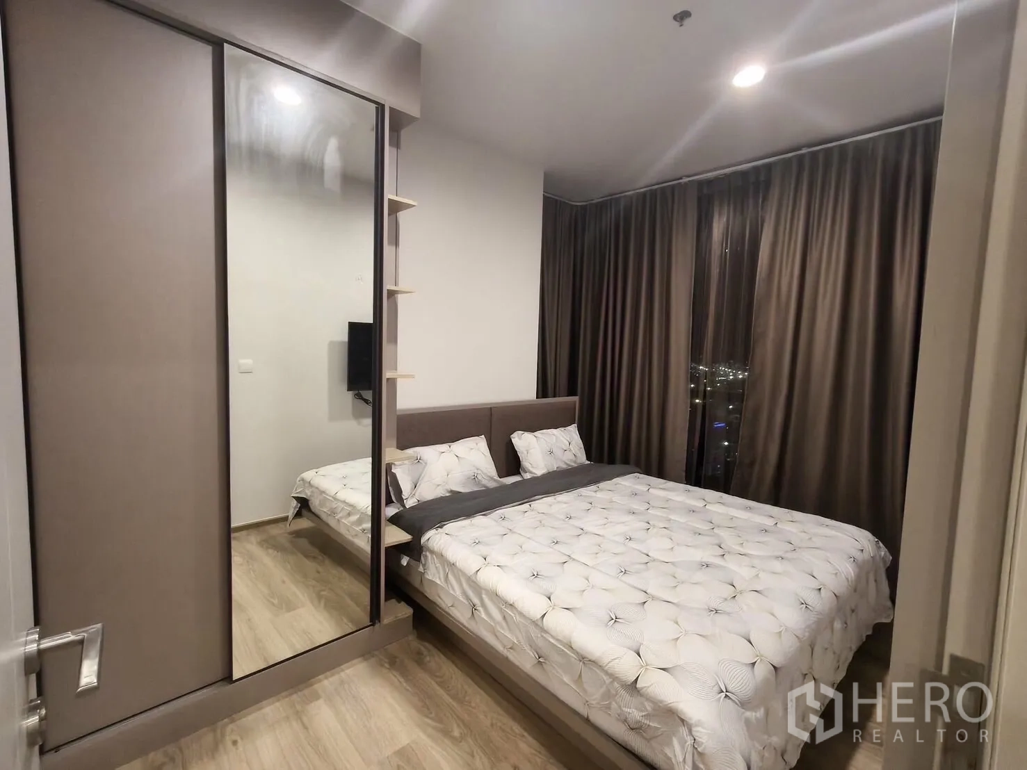 คอนโด for rent in Khlong Toei, Bangkok - มุมมองห้องนอนหลัก แสดงตู้เสื้อผ้าบานกระจกและหน้าต่างสูงเห็นแสงเมือง