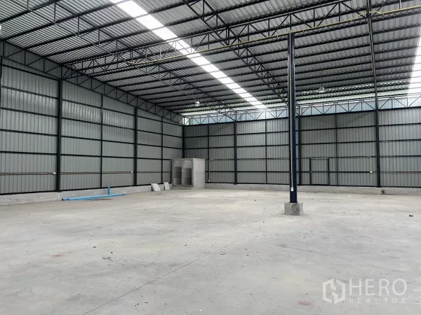 Warehouse for rent in Khlong Toei, Bangkok - Spacious warehouse interior with steel truss roof, skylight strips, and corner restrooms.