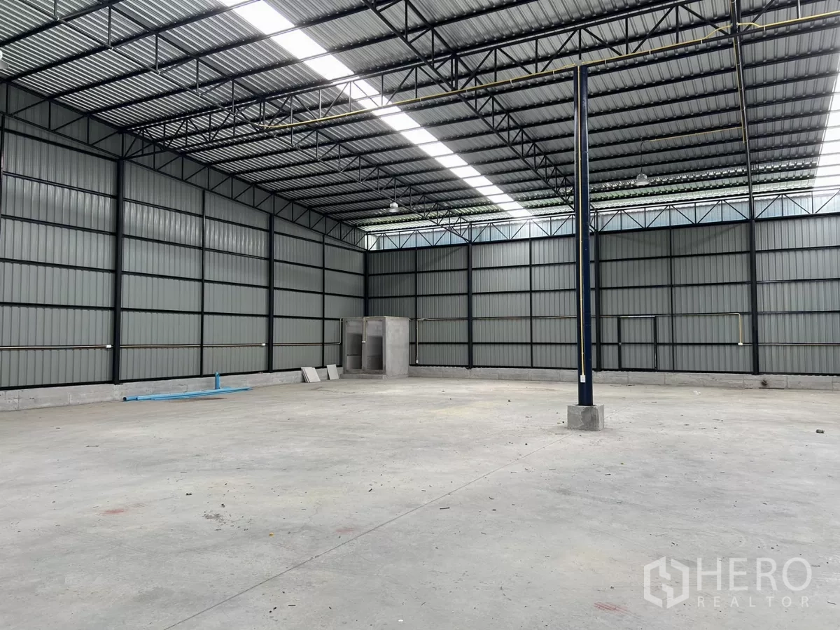 Warehouse for rent in Khlong Toei, Bangkok - Spacious warehouse interior with steel truss roof, skylight strips, and corner restrooms.