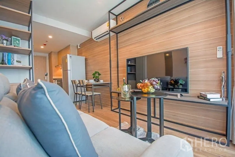 คอนโด ขายในRatchathewi, Bangkok - ห้องนั่งเล่นผนังไม้พร้อมชั้นวาง ทีวีจอแบน และมุมทานอาหารเล็ก