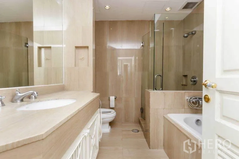 Condominium for rent or sale in Pathum Wan, Bangkok - Bright bathroom with glass-enclosed shower, built-in bathtub, and extended countertop sink.