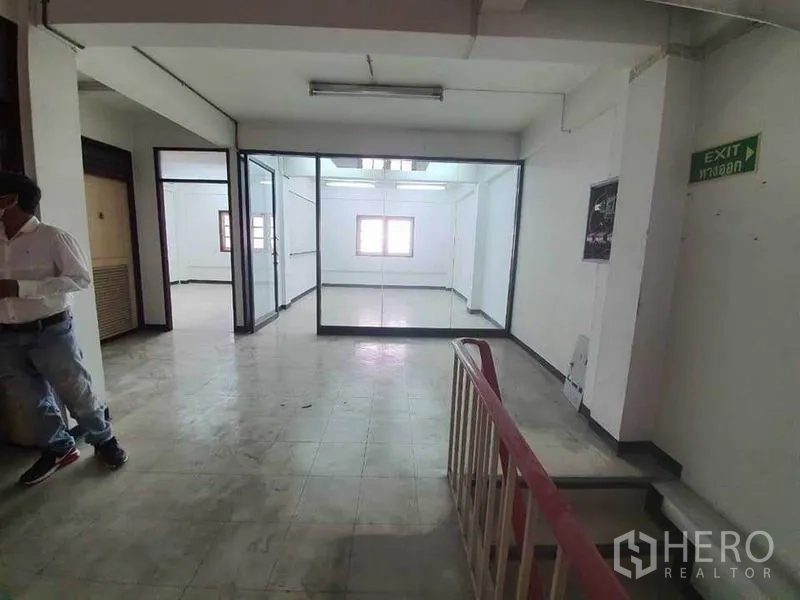 店屋 出租在Bang Rak, Bangkok - 走廊带出口标识、楼梯扶手及大型玻璃隔间的商用空间。