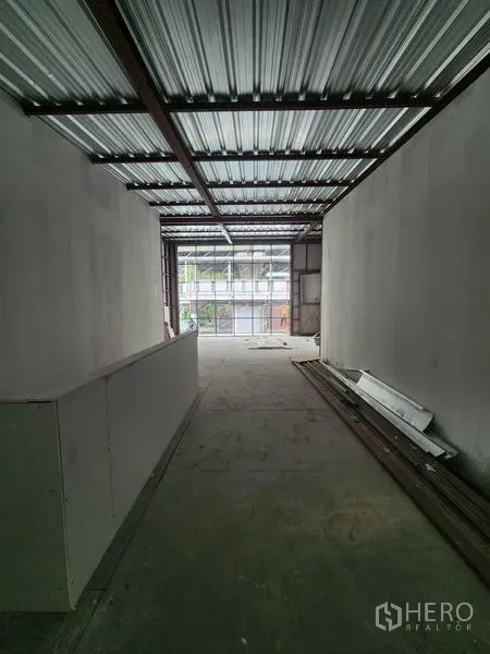 零售空间 出租在Khlong Toei, Bangkok - 狭长毛坯室内，金属屋顶、白墙与水泥地面，前方落地玻璃采光充足。