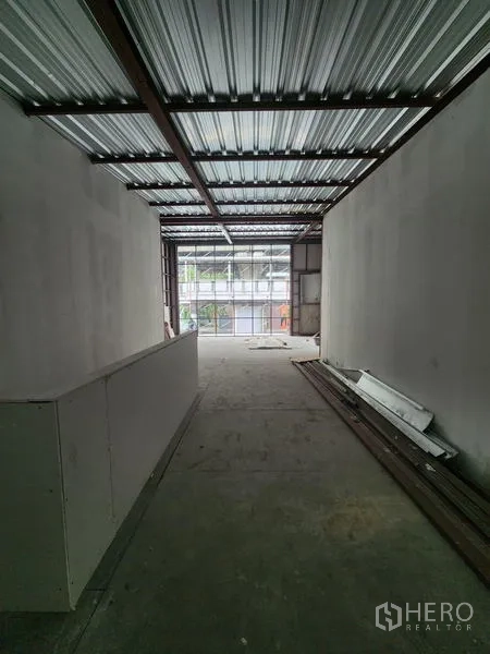 零售空间 出租在Khlong Toei, Bangkok - 狭长毛坯室内，金属屋顶、白墙与水泥地面，前方落地玻璃采光充足。