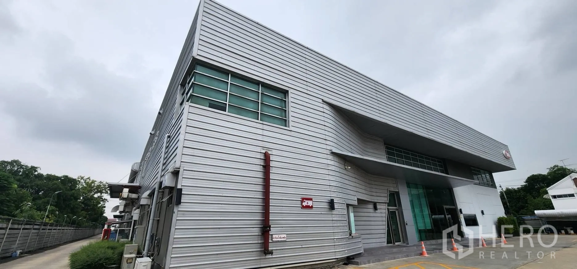 Warehouse for rent in Bang Sue, Bangkok - Side view of a metal-clad warehouse with windows and a service lane.