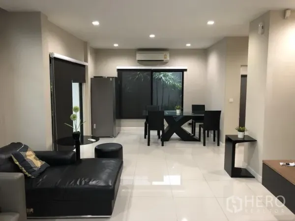 Detached House for rent in Bang Kapi, Bangkok - Dining area with glass table, large windows, and air conditioning overlooking greenery.
