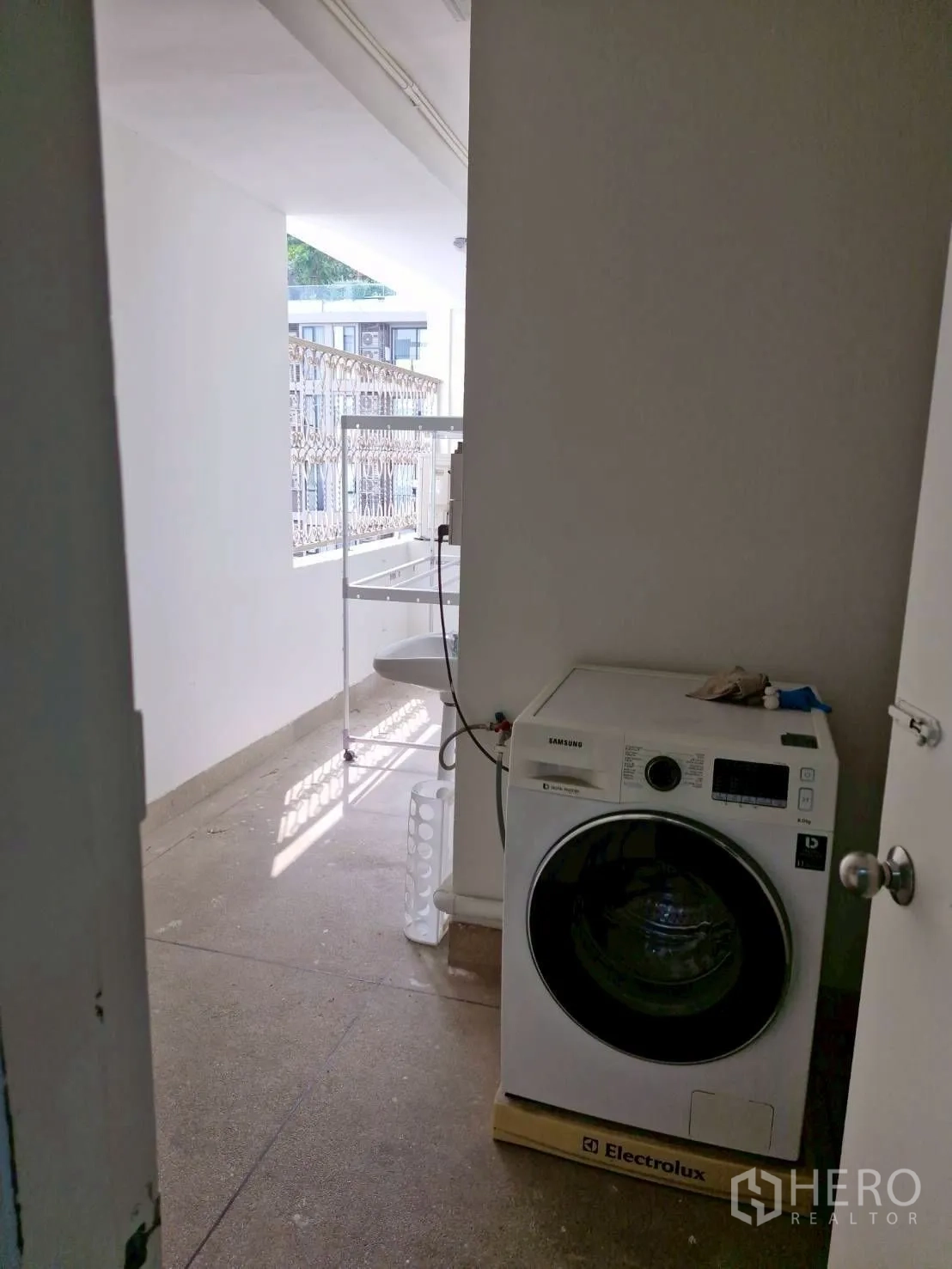 Condominium for rent in Khlong Toei, Bangkok - Utility balcony with front-load washing machine and a small sink by the railing.