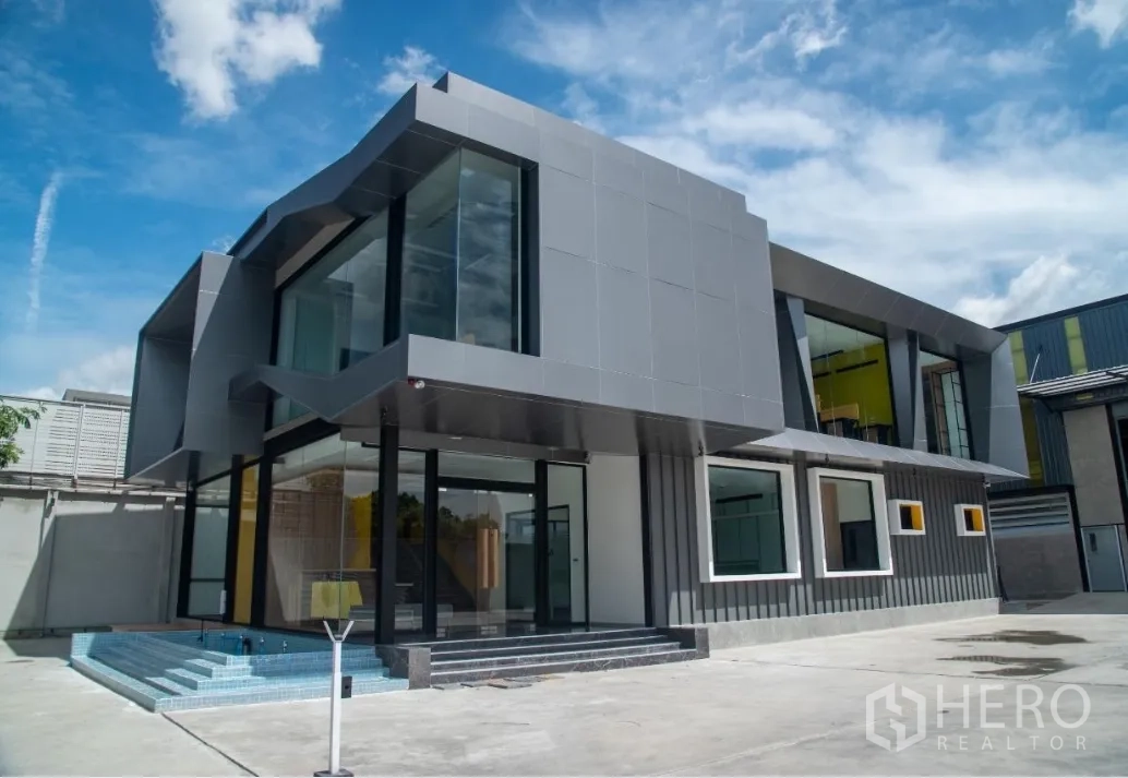 Warehouse for sale in Bang Khen, Bangkok - Corner glass facade with steps and blue‑tiled water feature at office entrance.