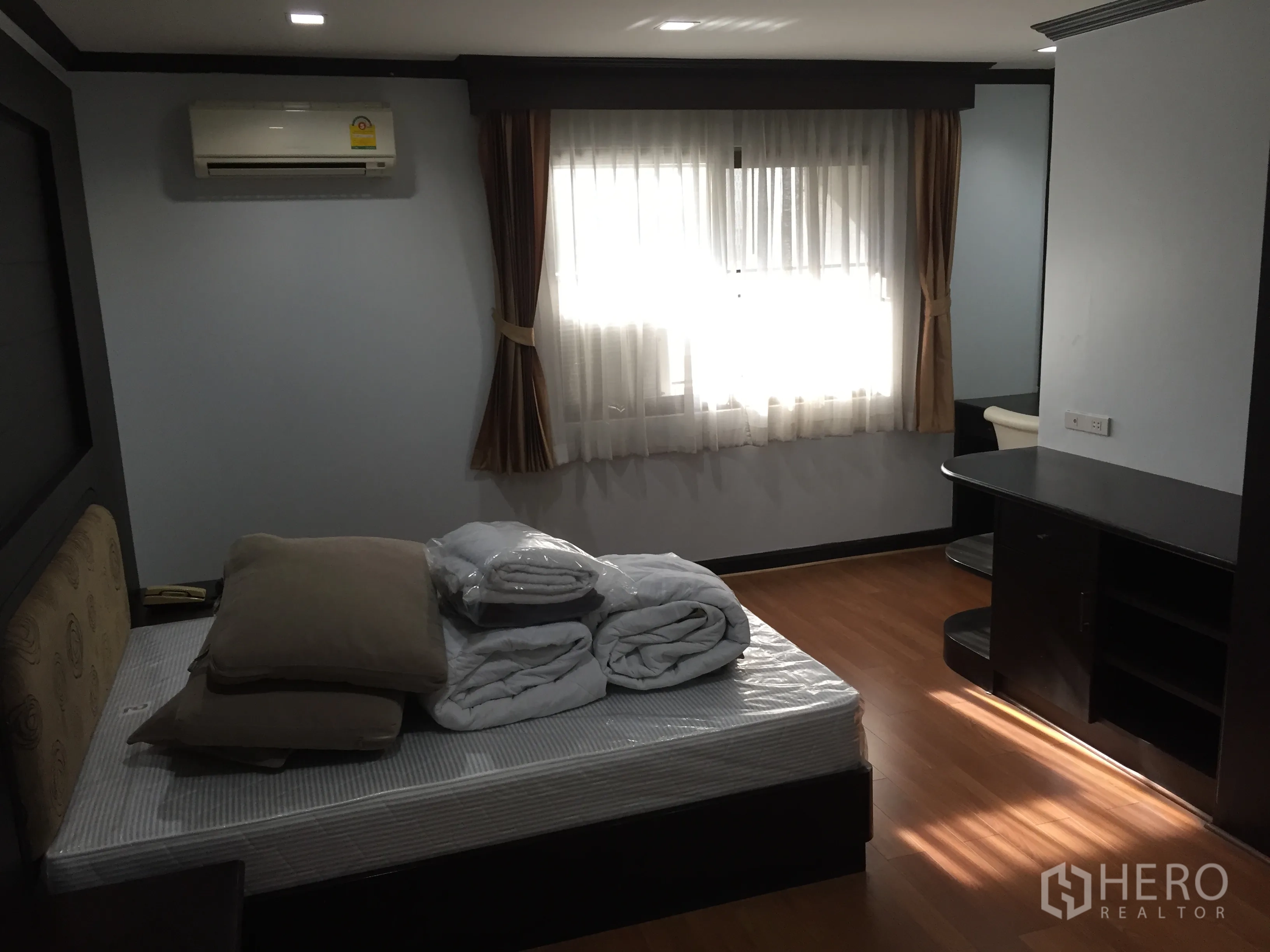 Condominium for rent in Watthana, Bangkok - Second bedroom featuring window drapes, air conditioning, and dark wood desk and shelving.