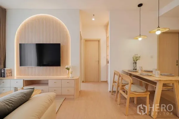 Condominium for rent in Watthana, Bangkok - Open-plan living and dining space with a TV feature wall and cozy seating.