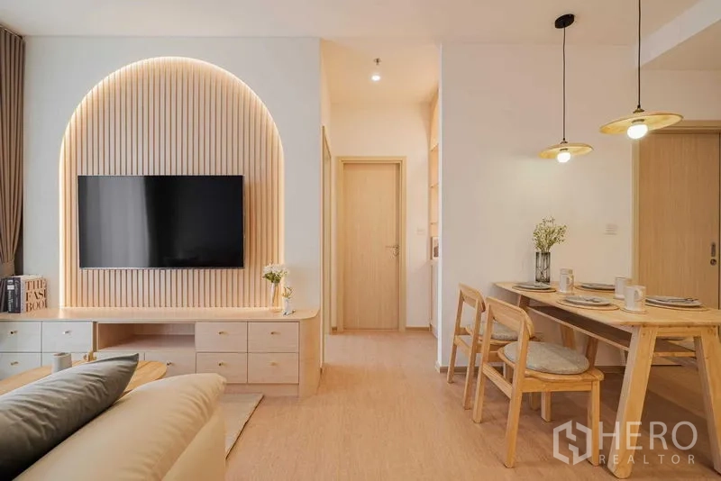 Condominium for rent in Watthana, Bangkok - Open-plan living and dining space with a TV feature wall and cozy seating.