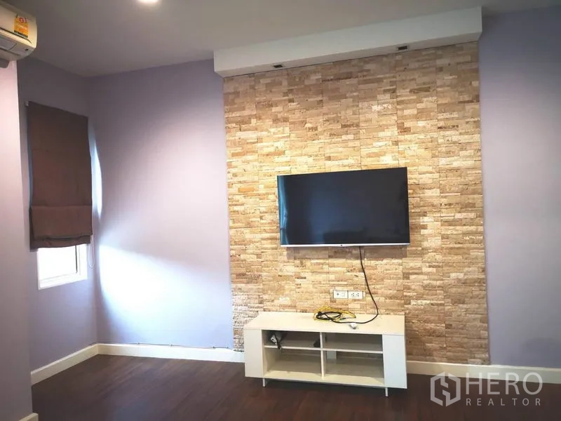 Townhouse for rent in Suan Luang, Bangkok - TV wall with stone cladding and media console in an upstairs living space.