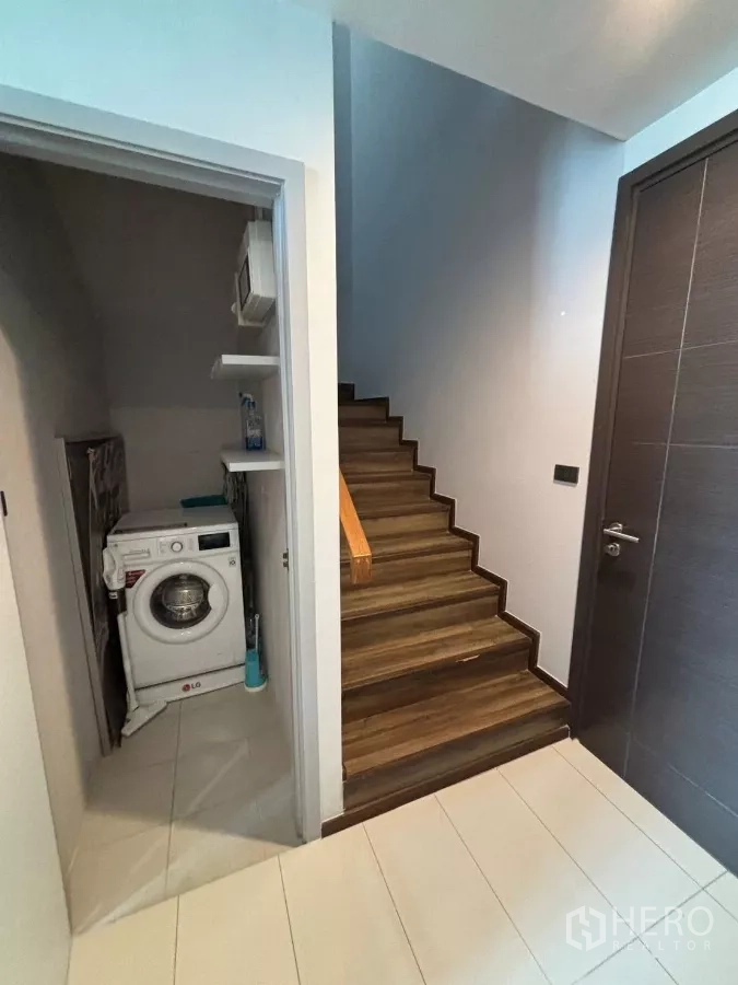 Condominium for rent or sale in Watthana, Bangkok - Laundry closet with washing machine next to a wooden staircase.