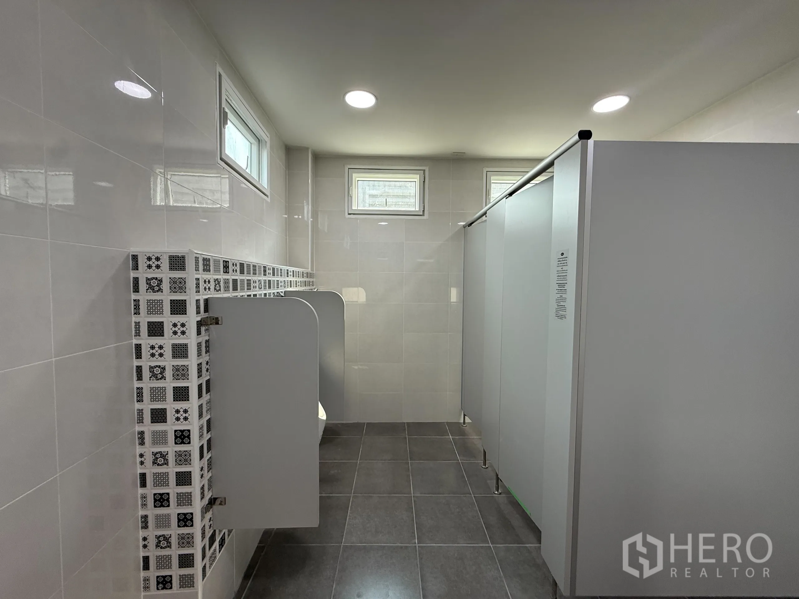 货栈 出租在Bang Khen, Bangkok - 员工卫生间设小便池与隔断厕间，墙地砖易于清洁维护。