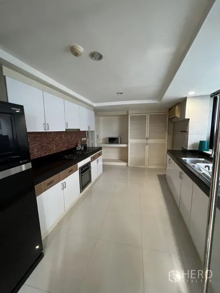 คอนโด ให้เช่า - ครัวแบบแกลลี ตู้สีขาว ท็อปหินสีดำ มีเตาอบและตู้เย็นขนาดใหญ่