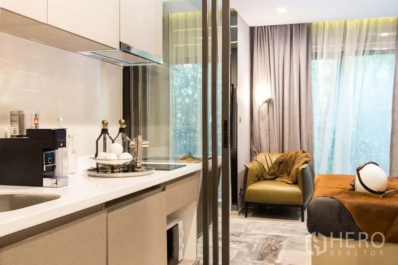 คอนโด ขายในRatchathewi, Bangkok - ครัวขนาดกะทัดรัด เคาน์เตอร์สีขาวและเครื่องใช้ไฟฟ้า อยู่ติดมุมนั่งเล่นและเตียง