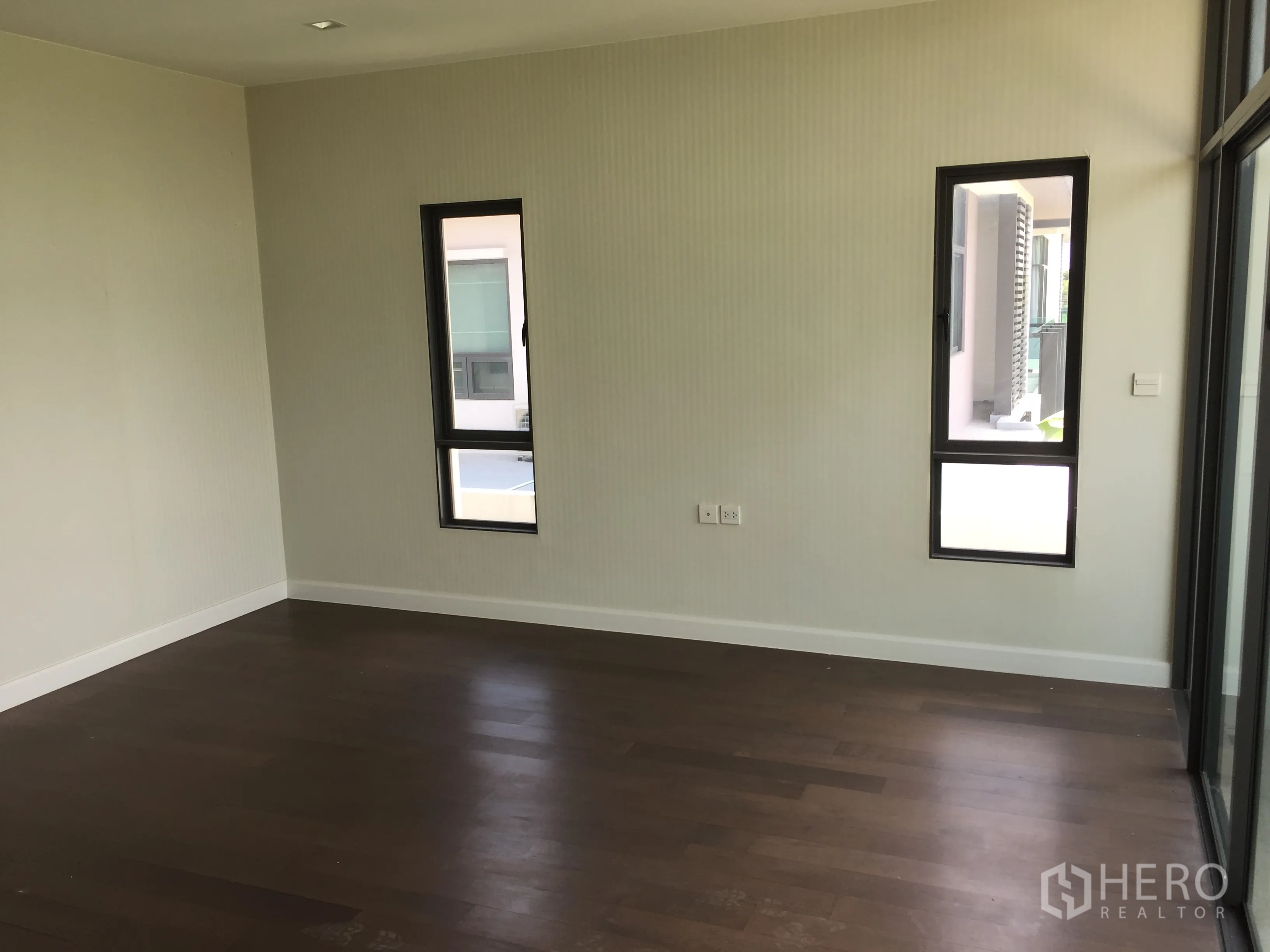 Detached House for rent or sale in Prawet, Bangkok - Bright bedroom with wood flooring and slim vertical windows.