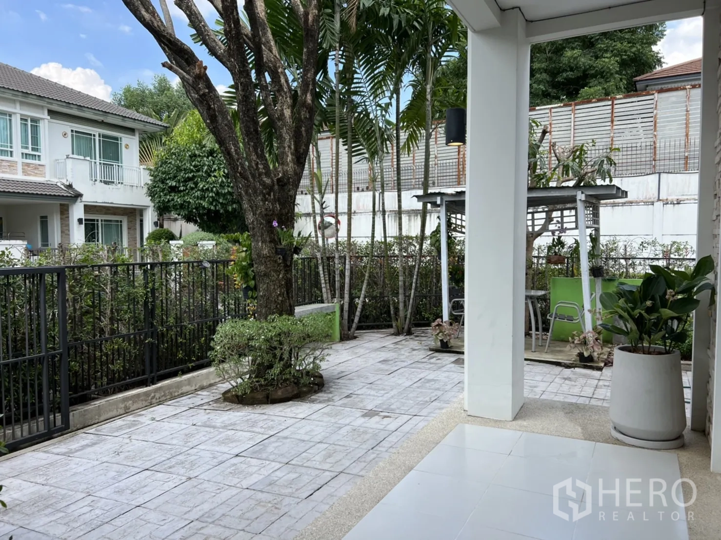 Detached House for rent in Bang Kapi, Bangkok - Tiled front patio garden with mature trees, a small gazebo, and metal fencing.