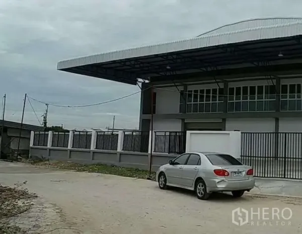 货栈 出租在Bang Bo, Samut Prakan - 仓库侧视图，围栏与加长雨棚，临路出入口。