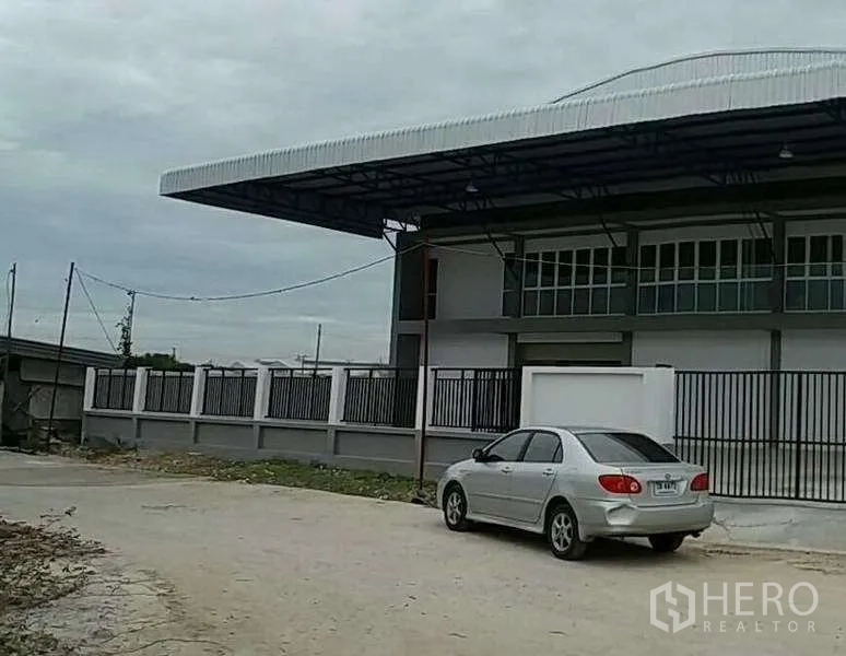 货栈 出租在Bang Bo, Samut Prakan - 仓库侧视图，围栏与加长雨棚，临路出入口。