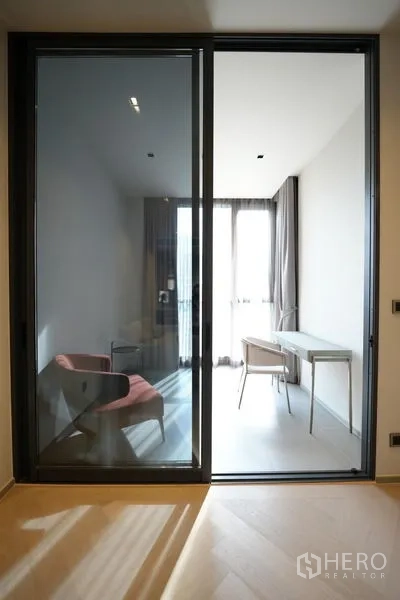 Condominium for rent - Sliding glass partition revealing a light-filled study with desk and chair by floor-to-ceiling windows.